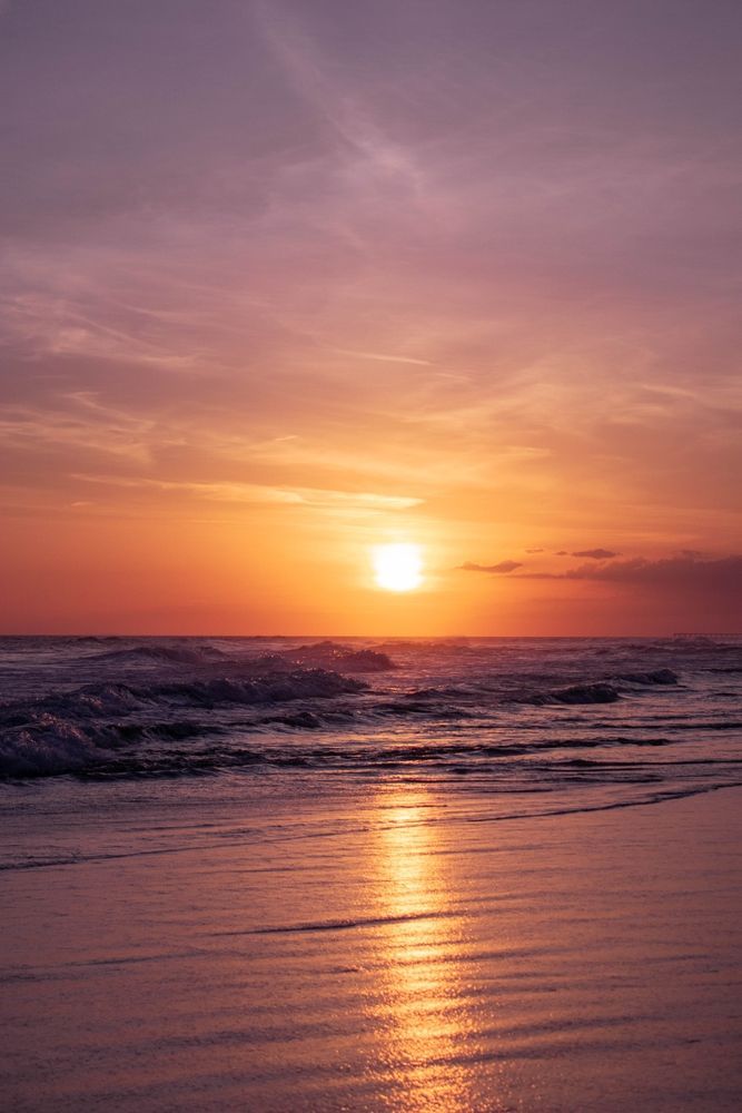 The sun is setting over the ocean and reflected in the water.