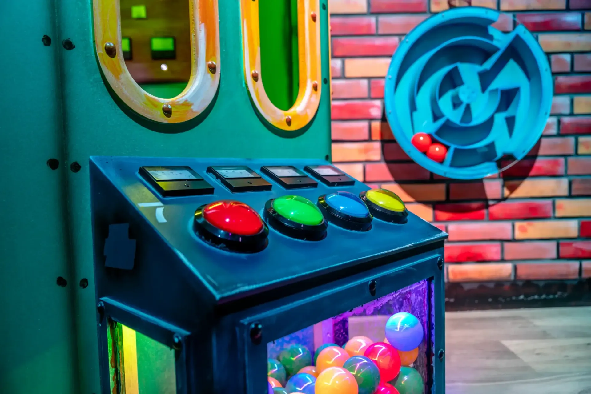 Een machine gevuld met gekleurde ballen staat voor een bakstenen muur.