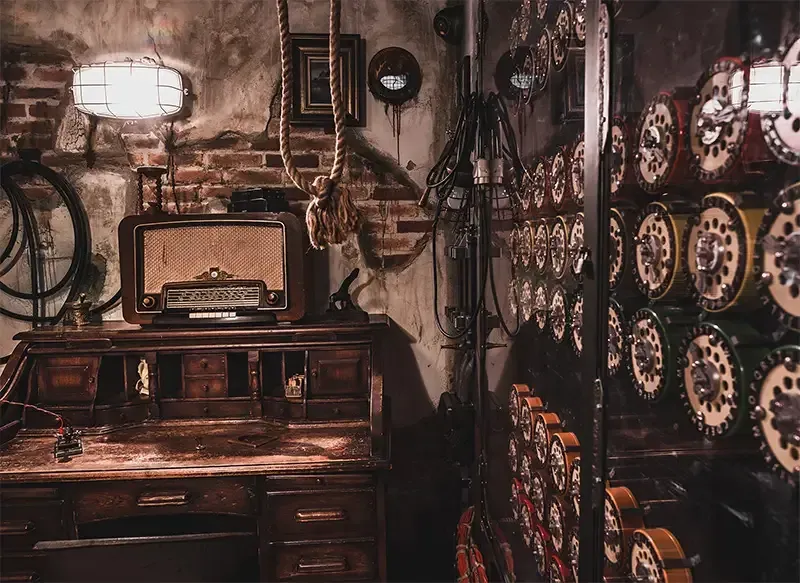 De imitation room  met een bureau, radio, klokken en een bakstenen muur.