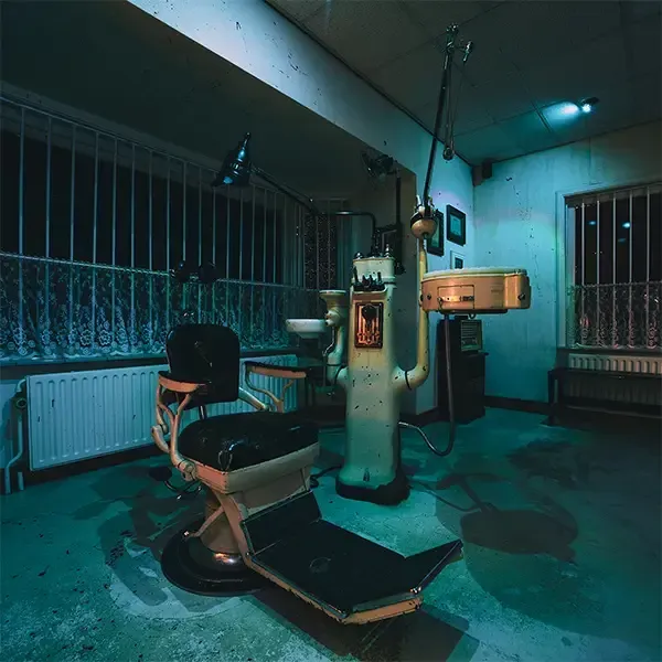 Een donkere kamer met een tandartsstoel en een wastafel