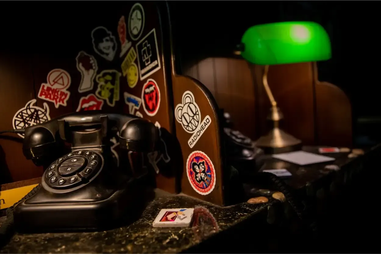 Een zwarte telefoon staat op een tafel naast een groene lamp.