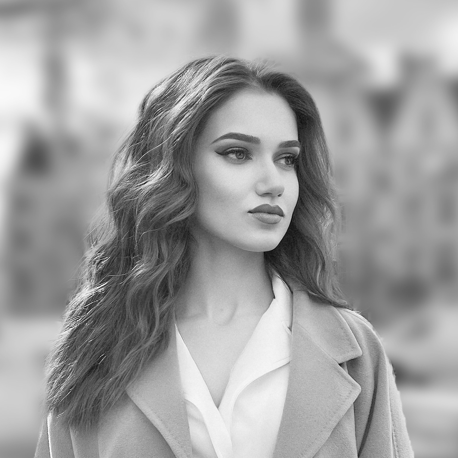 A black and white photo of a woman wearing a coat and a white shirt.