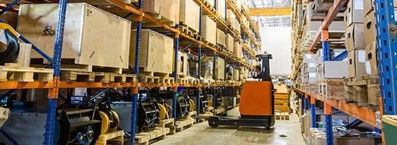 A forklift is driving through a warehouse filled with shelves and boxes.