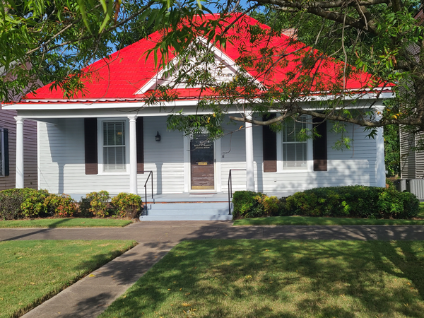 A white house with a red roof and black shutters