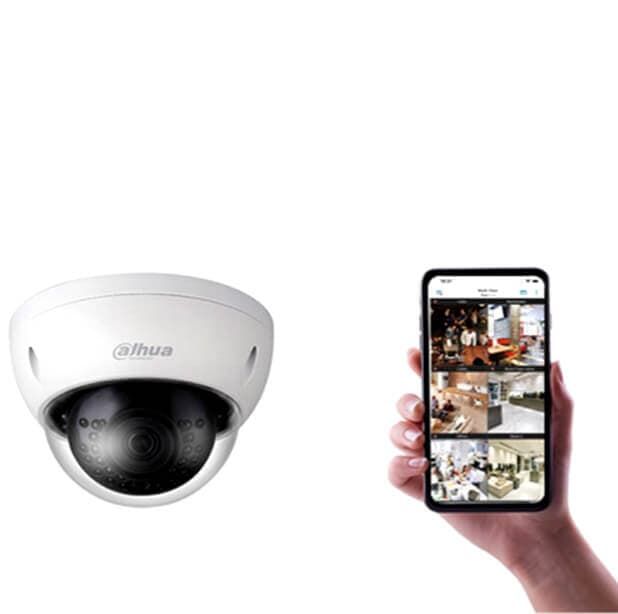 Cámara de seguridad tipo domo blanca junto a una mano que sostiene un teléfono inteligente mostrando imágenes de la cámara en directo.