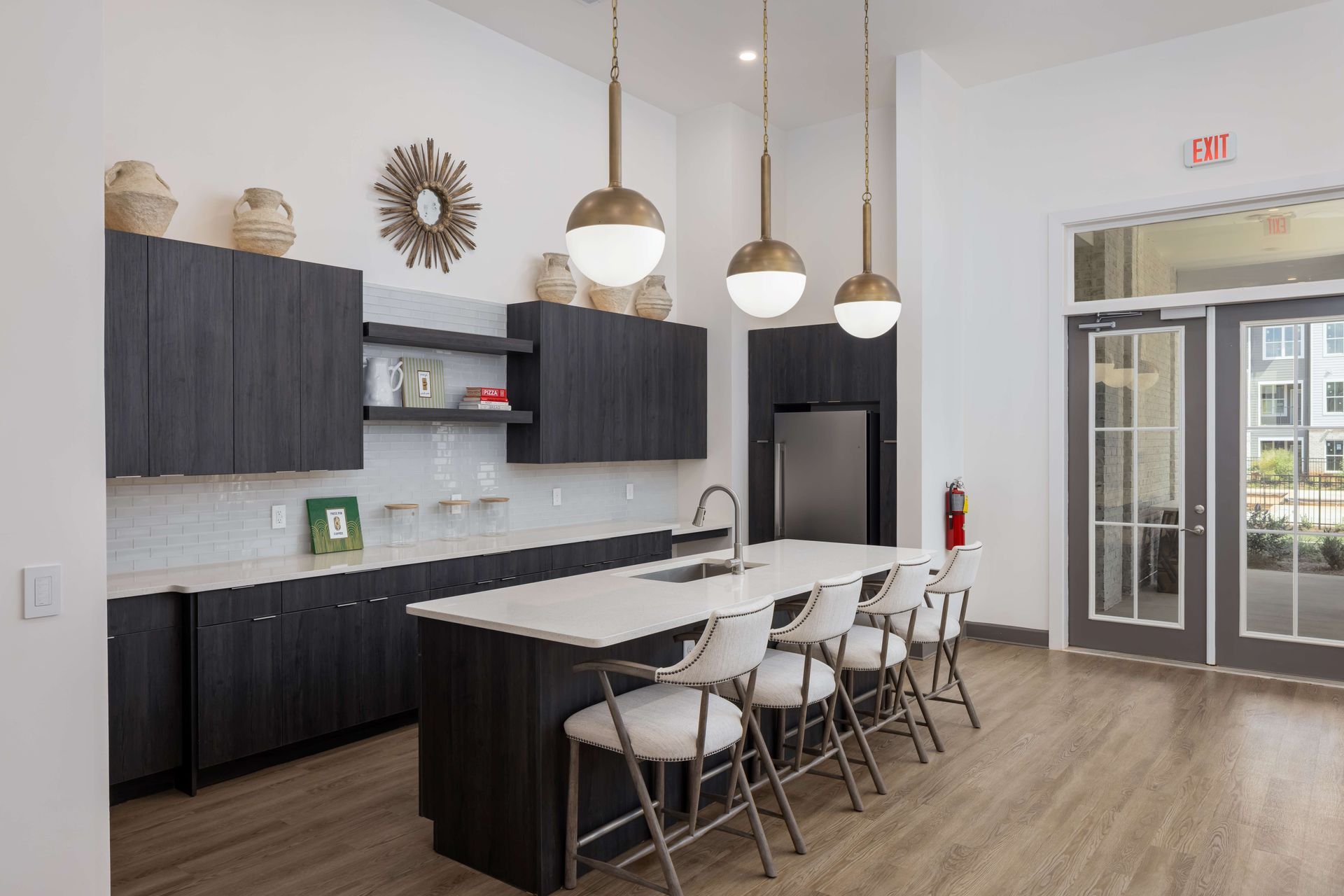 Kitchen area with dark cabinets, white countertops, island with stools, and pendant lights.