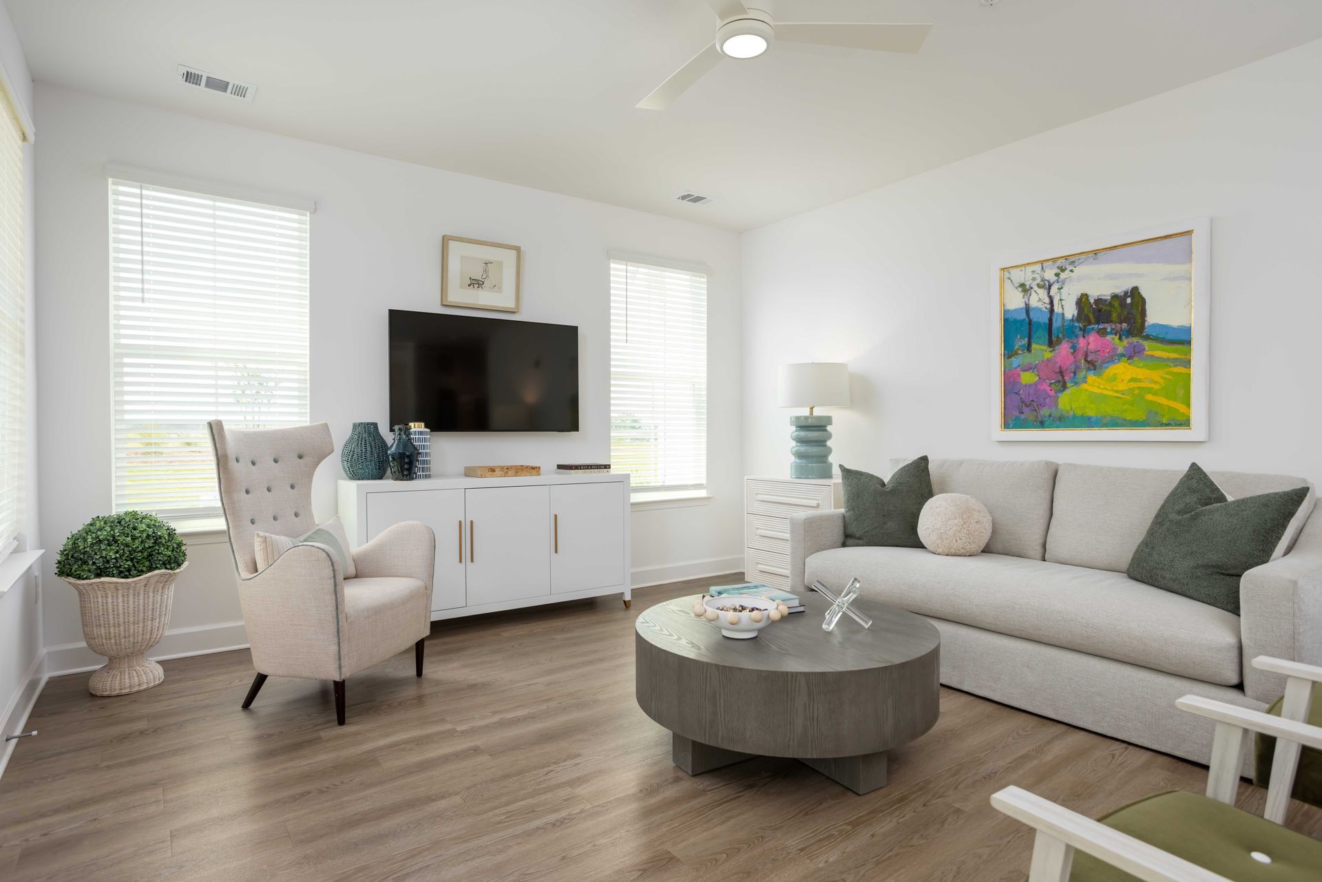 Living room with white walls, a white cabinet, a sofa with green pillows, and a round gray coffee table.