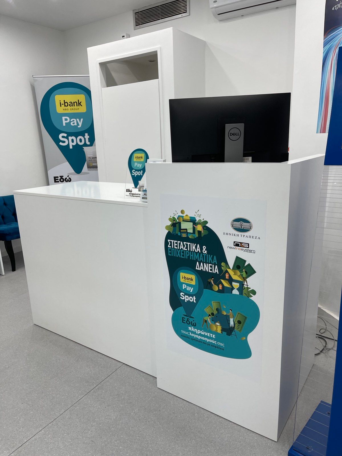 Λευκό γραφείο υποδοχής με υπολογιστή και διαφημιστικά αυτοκόλλητα σε ένα καλά φωτισμένο γραφείο.