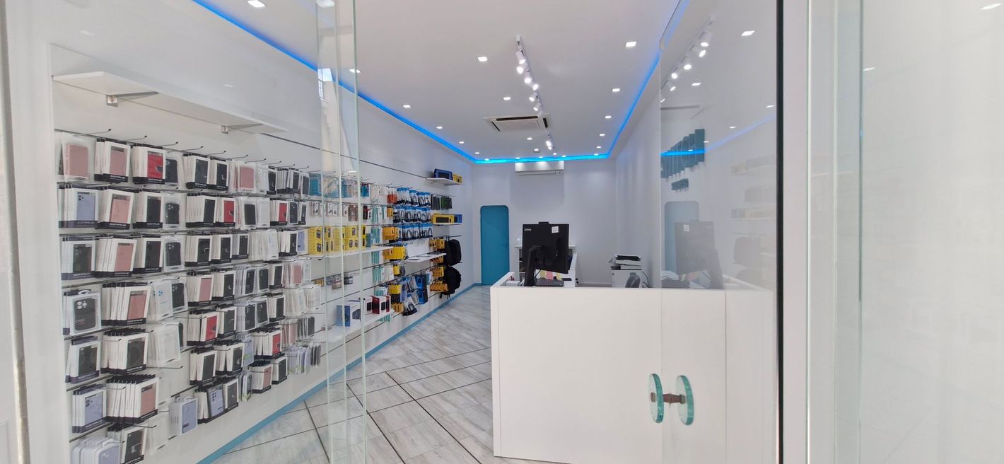Εσωτερικό ενός έντονα φωτισμένου καταστήματος αξεσουάρ τηλεφώνων, λευκοί τοίχοι, γυάλινες προθήκες και μπλε διακοσμητικά.