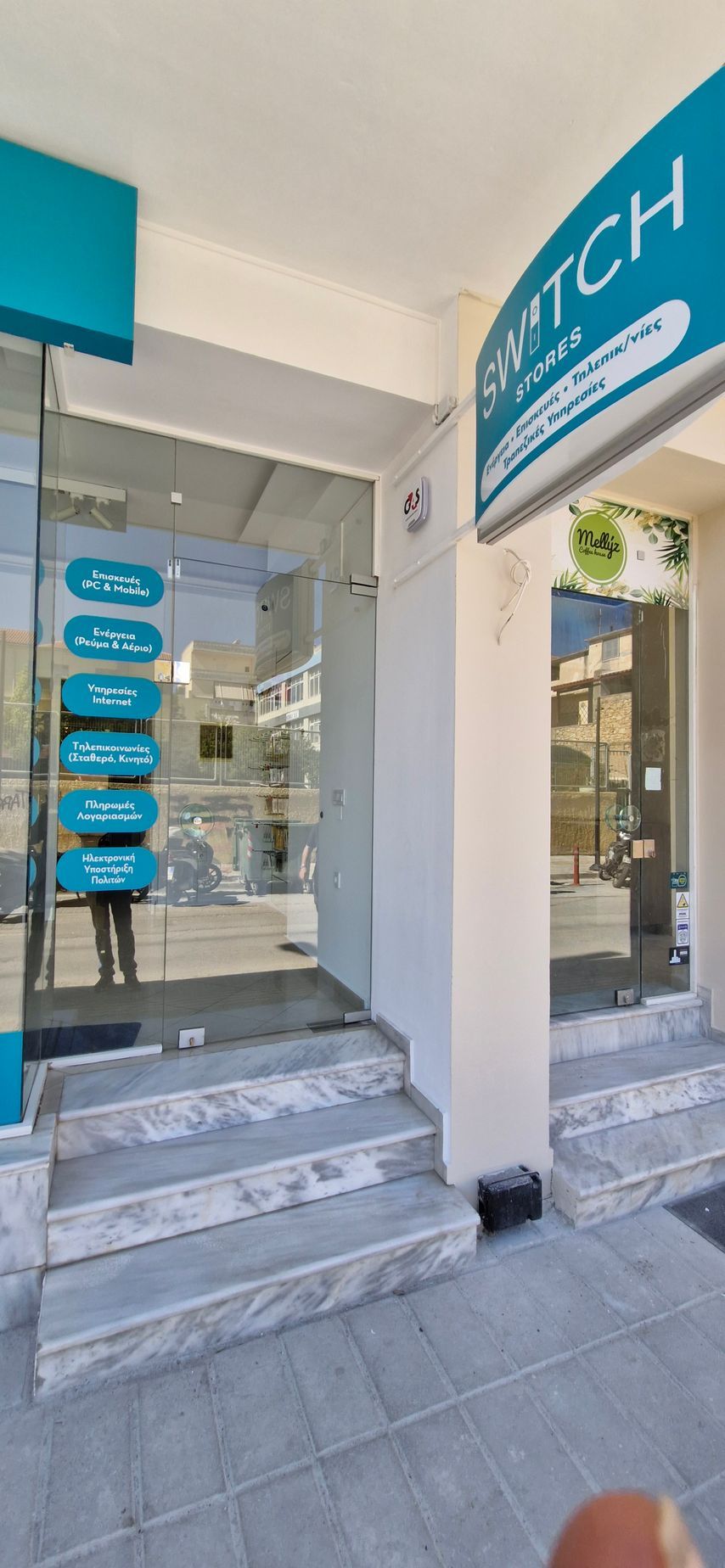 Εξωτερικό της Κλινικής Switch με γαλαζοπράσινη πινακίδα και γυάλινες πόρτες. Σκαλοπάτια οδηγούν στην είσοδο.