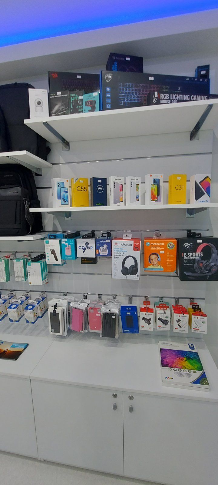 Ράφια που εκθέτουν αξεσουάρ κινητών τηλεφώνων σε ένα φωτεινά φωτισμένο κατάστημα.