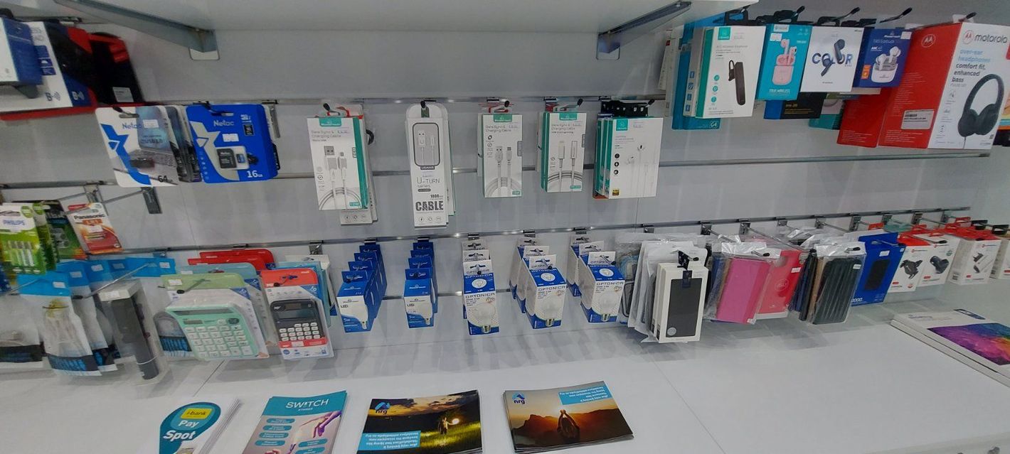 Μια έκθεση με συσκευασμένα αξεσουάρ τηλεφώνου σε ράφι καταστήματος, όπως φορτιστές, καλώδια και θήκες.