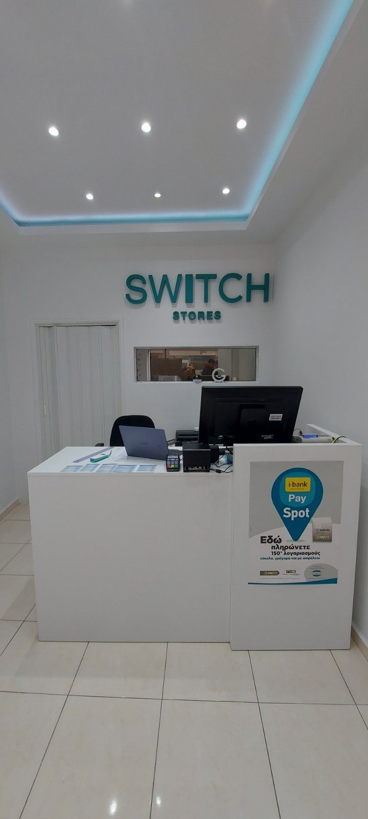 Ένας χώρος υποδοχής των καταστημάτων Switch. Ένα λευκό γραφείο βρίσκεται κάτω από μια πράσινη πινακίδα 