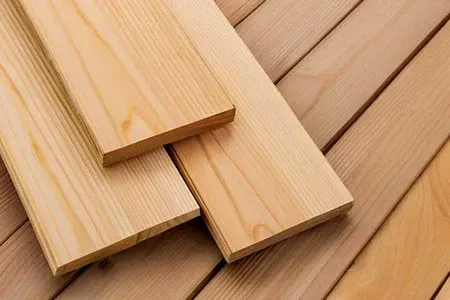 Three light-colored, unfinished wooden boards layered on top of a surface made of similar wooden planks.