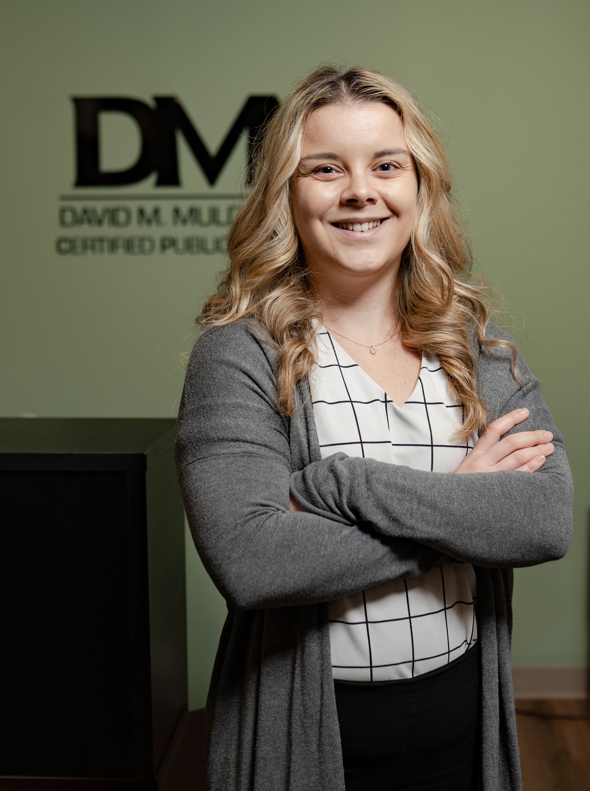 A woman is standing with her arms crossed in front of a sign that says dm.