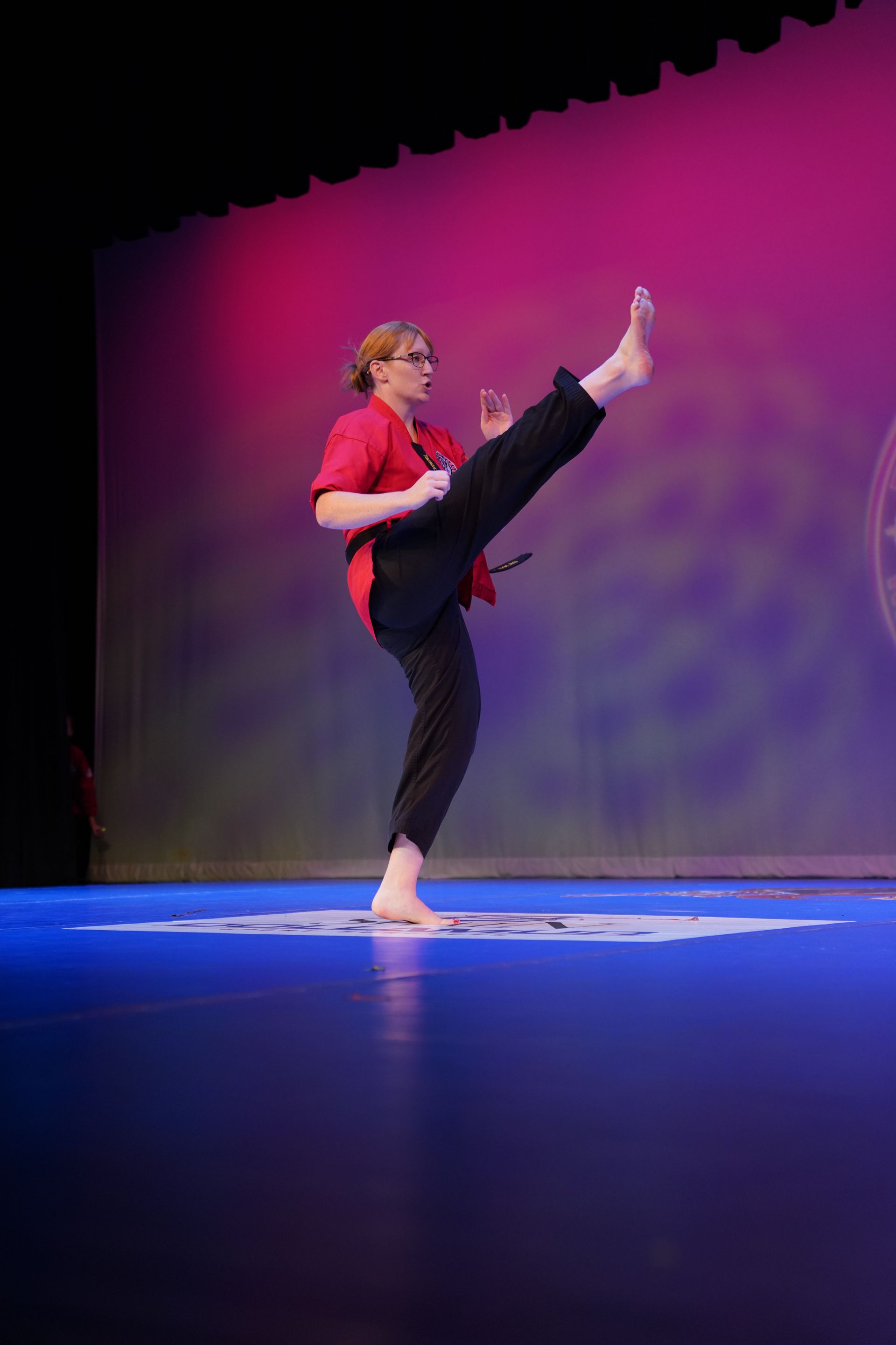A woman is doing a karate kick on a stage.