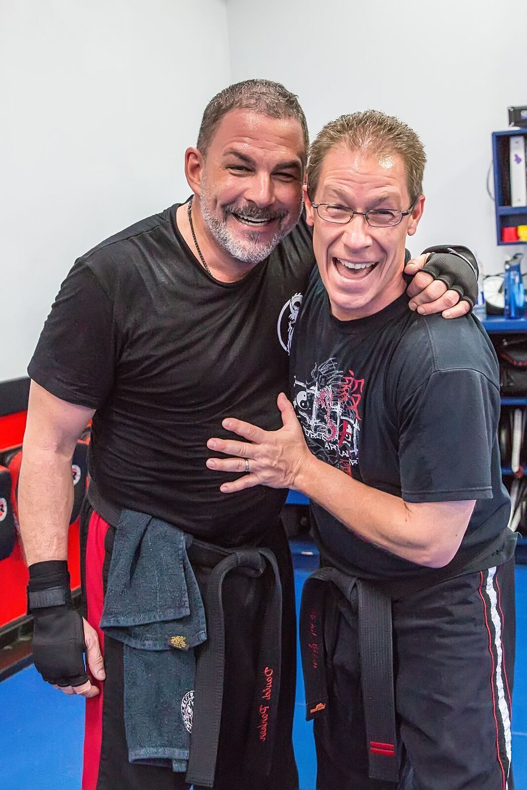 Two men are posing for a picture together in a gym.