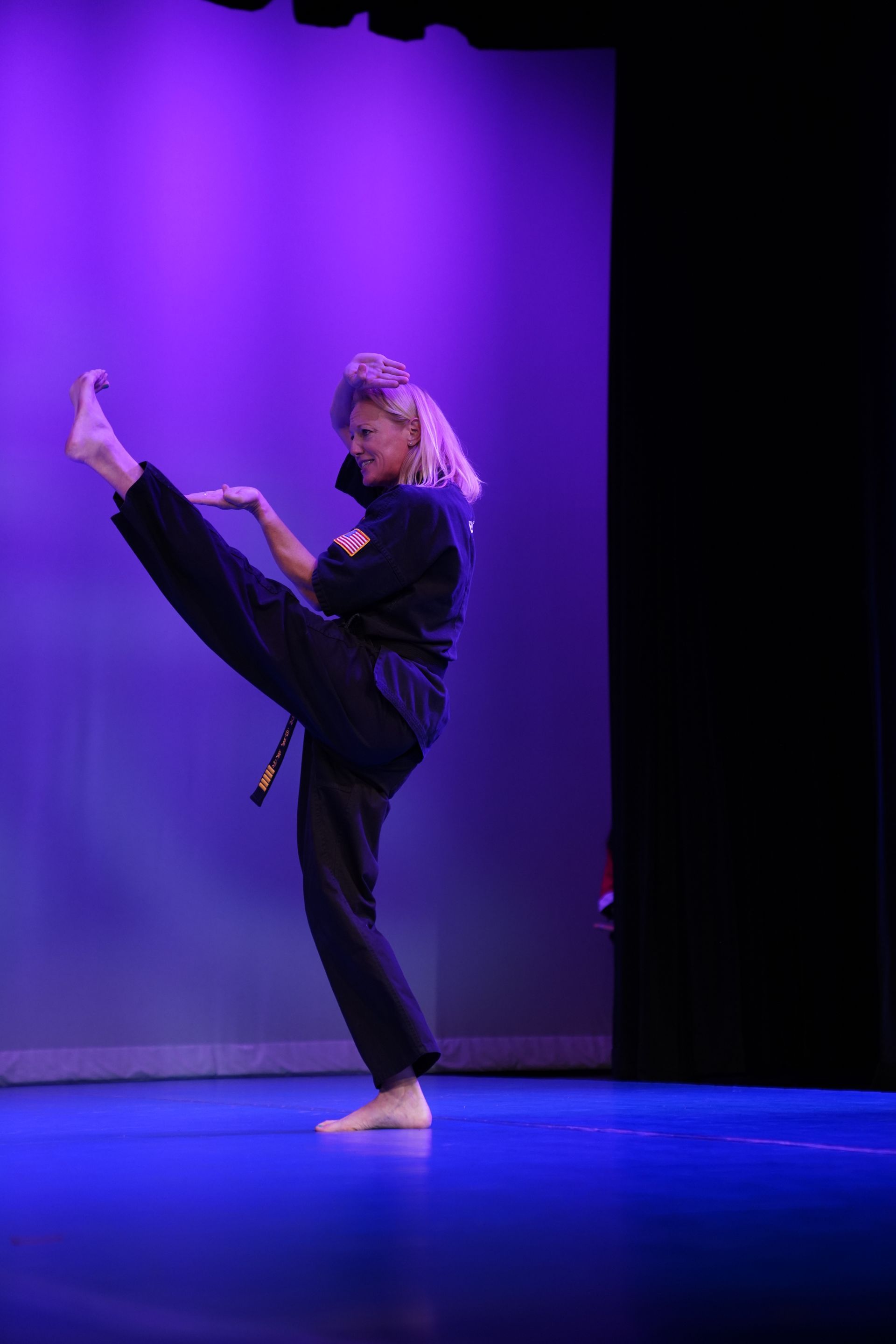 A woman is doing a karate kick on a stage.