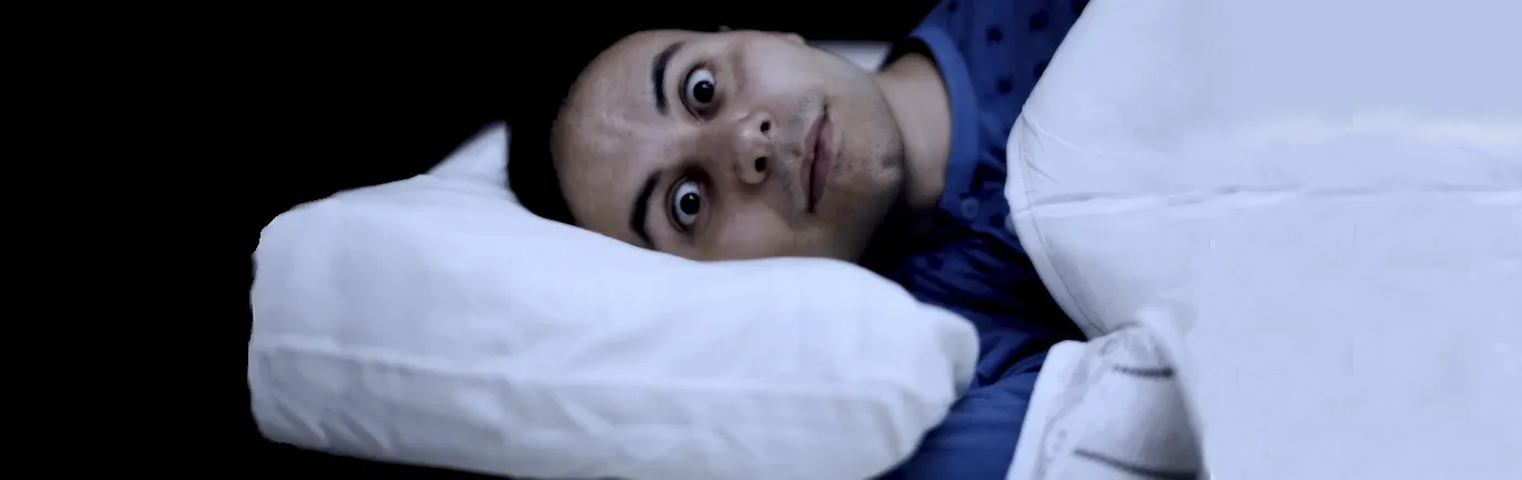 Caucasian man is wide awake in bed and can't sleep.