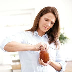 woman having difficulty opening a jar