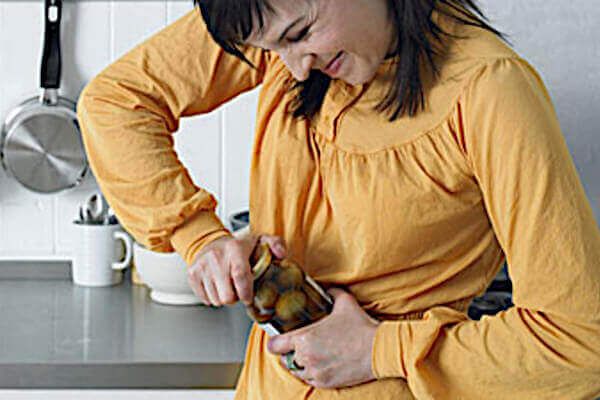 Young brunette woman having trouble opening a jar.