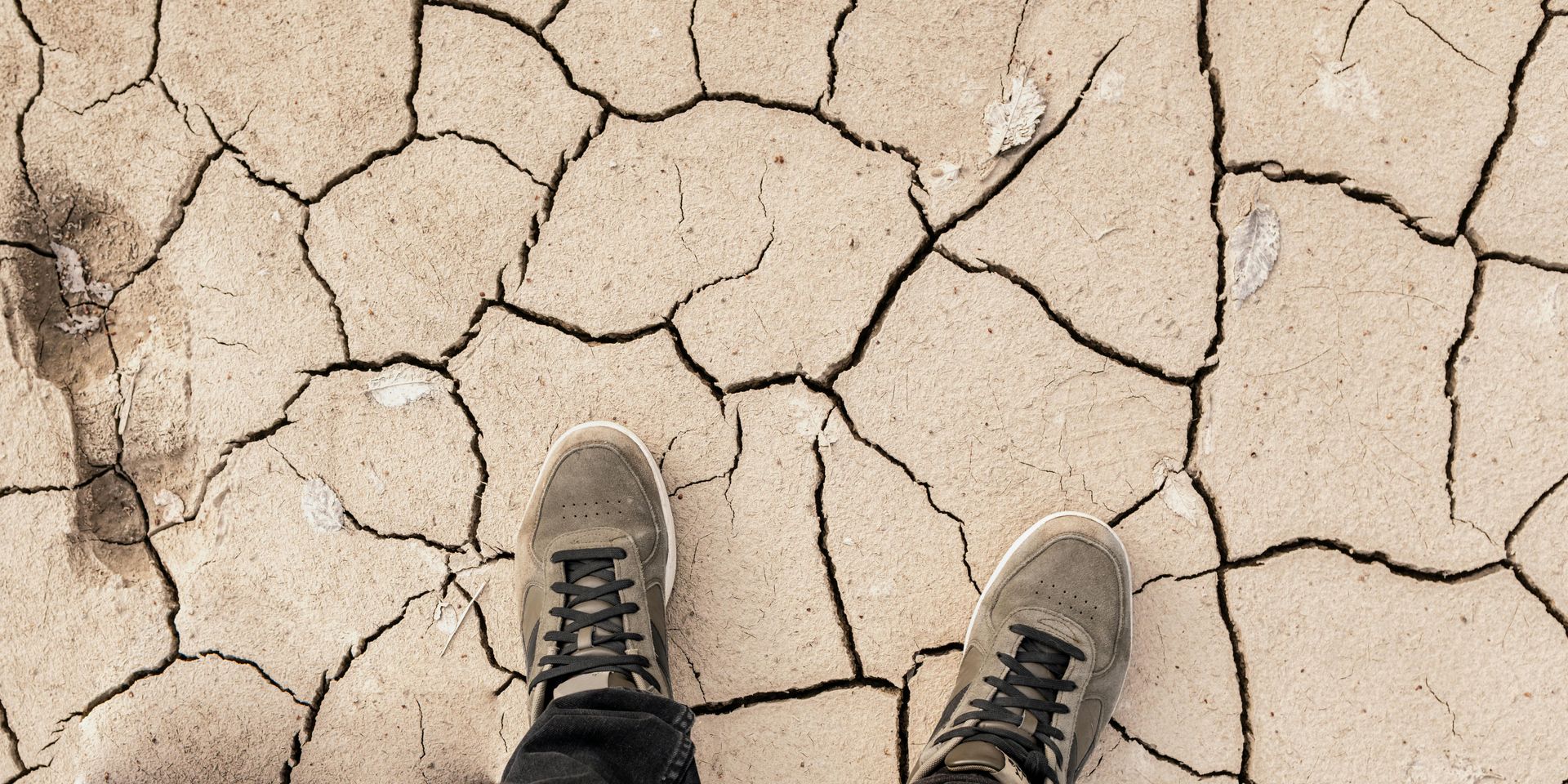 person's feet on dehydrated ground