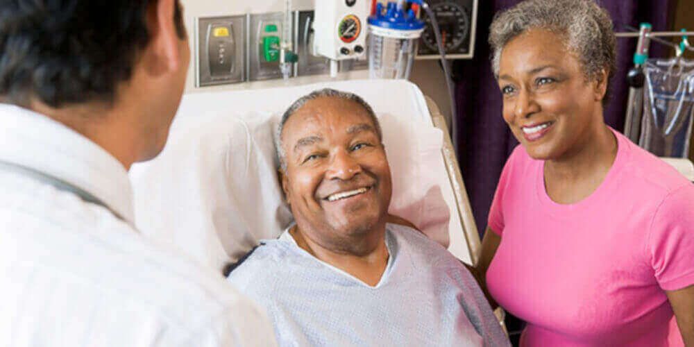 man in a hospital bed talks with his doctor