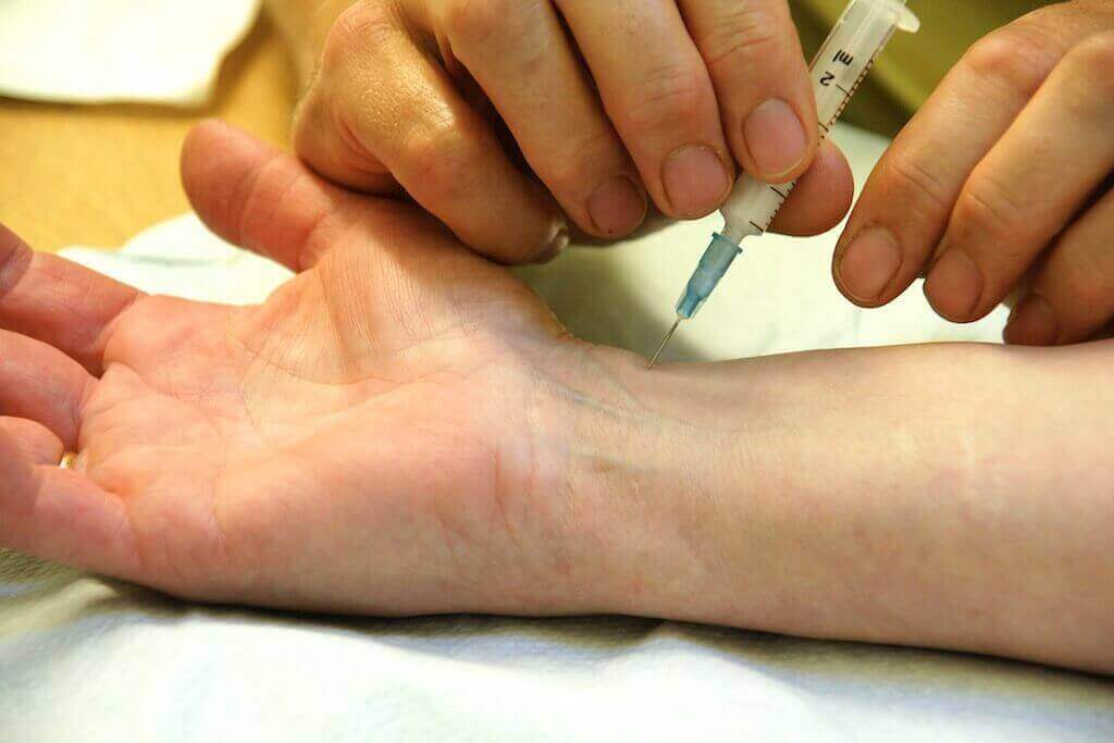 A doctor gives a patient a steroid shot in the wrist to relieve carpal tunnel pain.