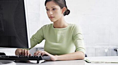 Young brunette woman typing on a computer.