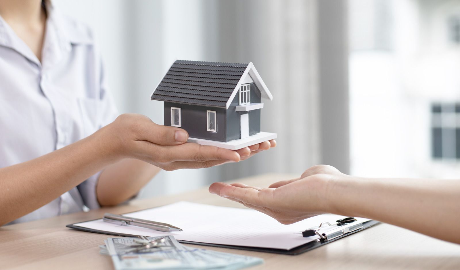 A woman is handing a model house to a man.