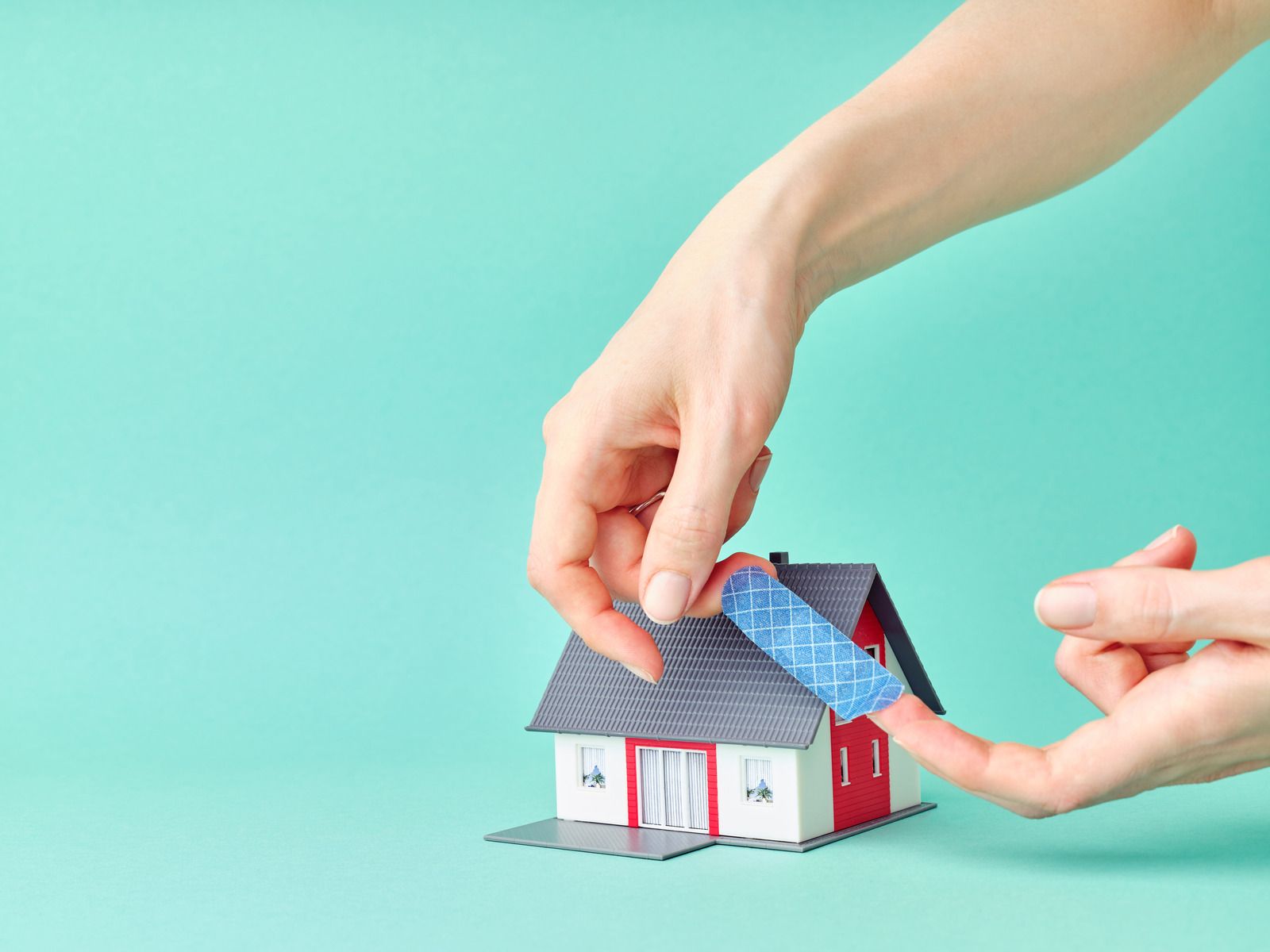 A person is putting a bandage on a model house.