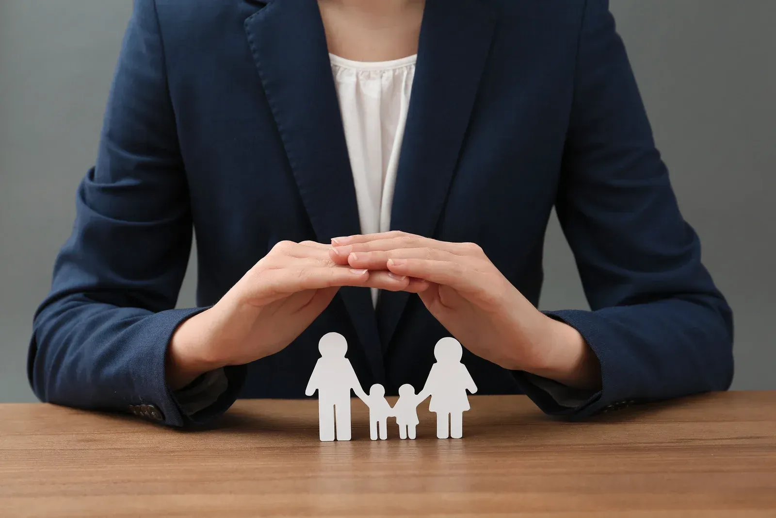 A woman is sitting at a table holding a paper cut out of a family.