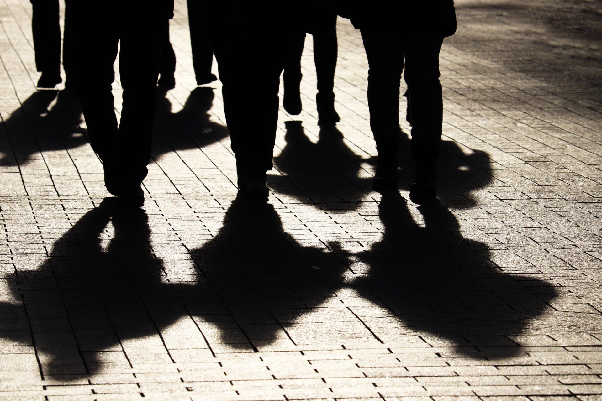 Silhouettes of a group of people walking along a pavement.