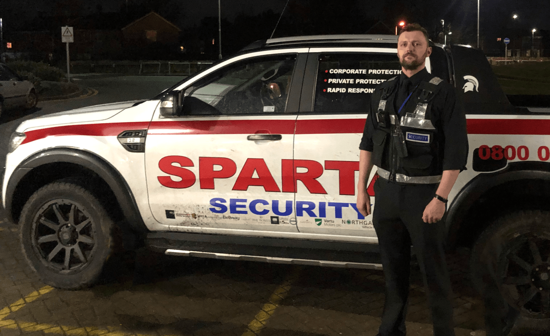 A security officer stood beside a super shiny Sparta Security truck, looking all dapper.