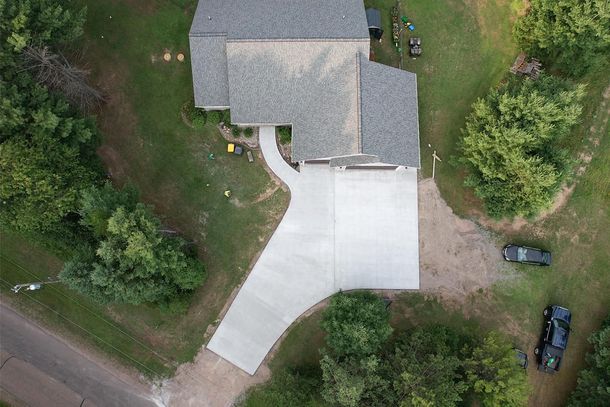 An aerial view of a house with a concrete driveway and a car parked in front of it.