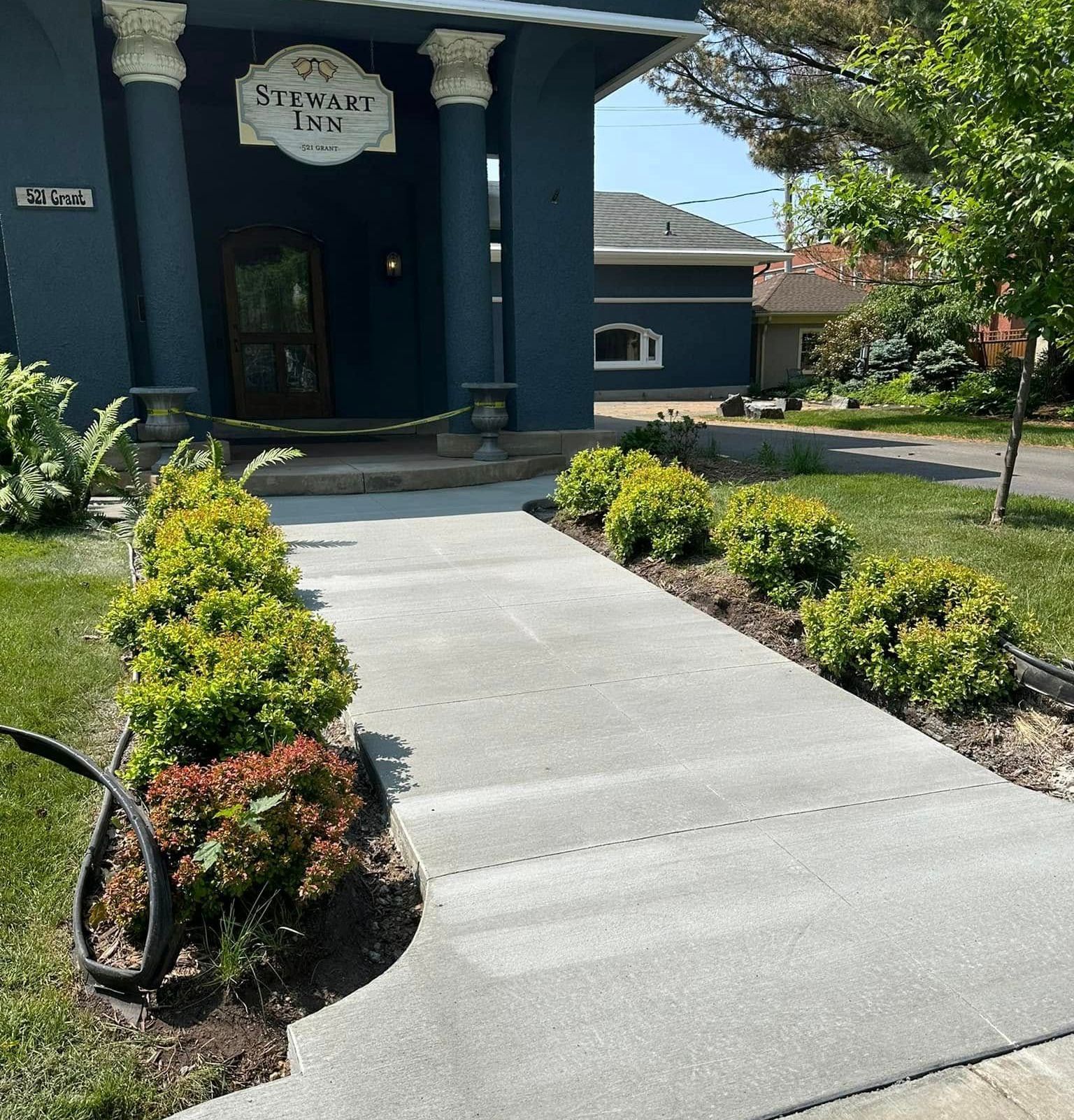 A concrete driveway surrounded by gravel and trees with a blue sky in the background.