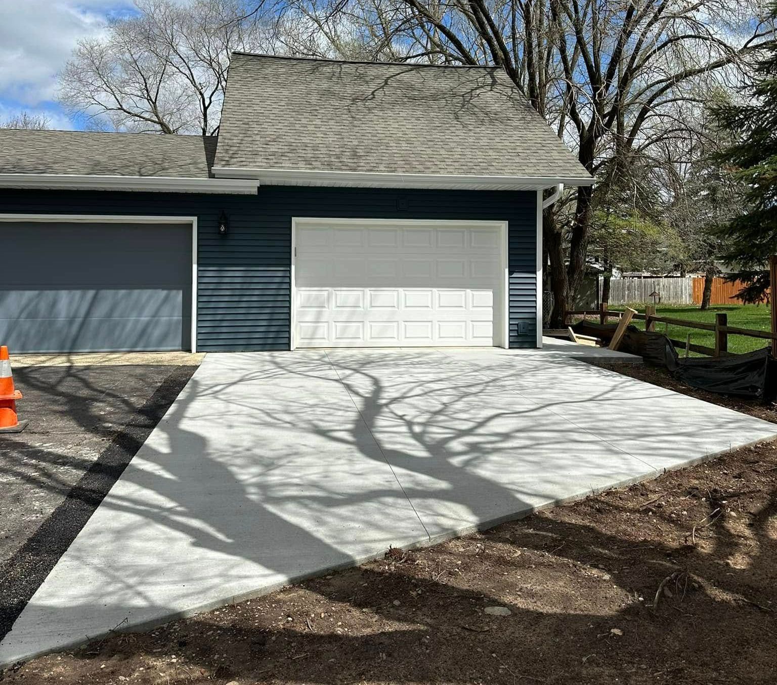 A blue house with a white garage door and a concrete driveway.