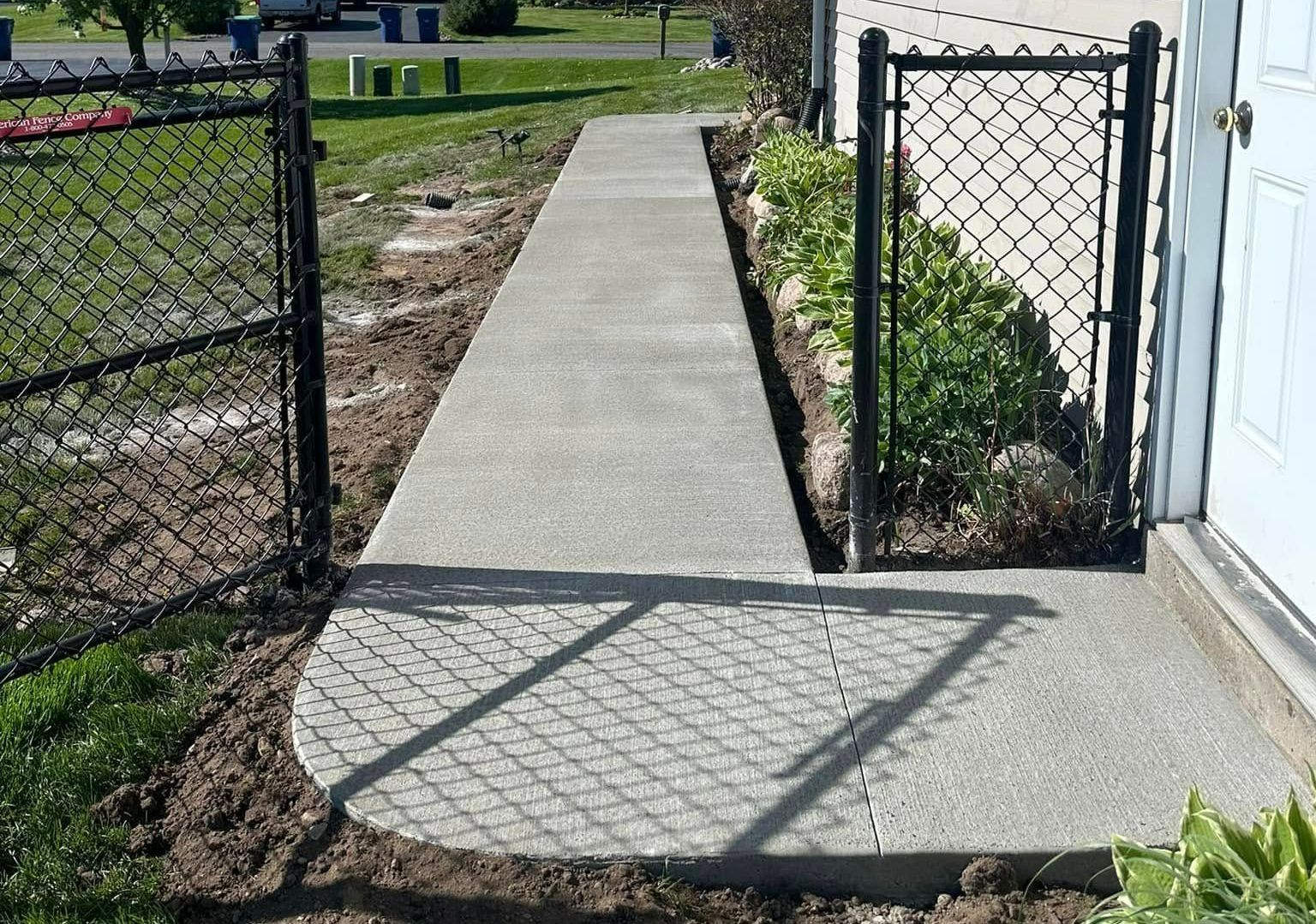 A concrete walkway next to a chain link fence