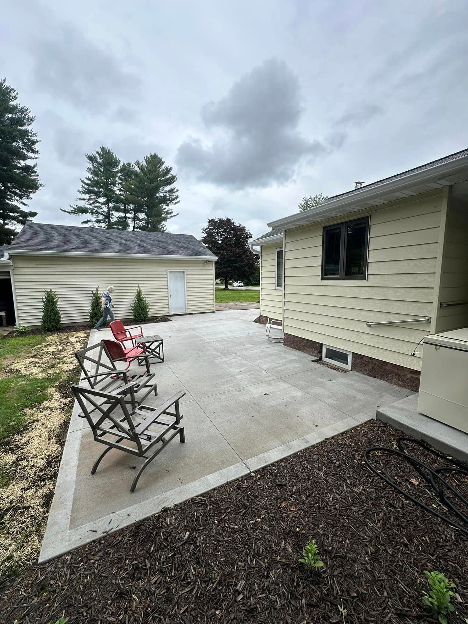 A patio with chairs and a fire pit in front of a house.