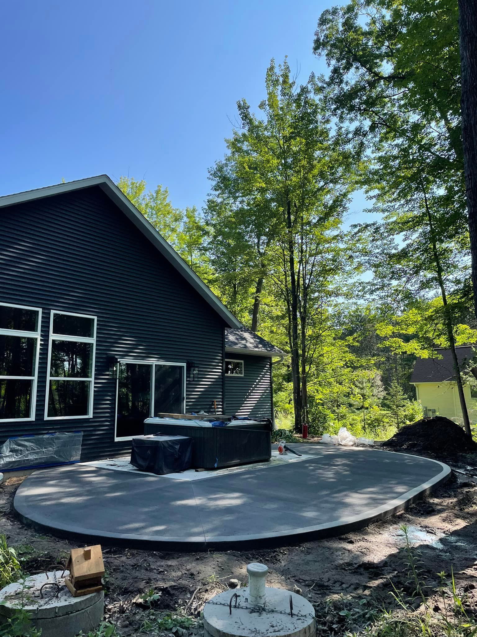 A black house with a patio in front of it surrounded by trees.