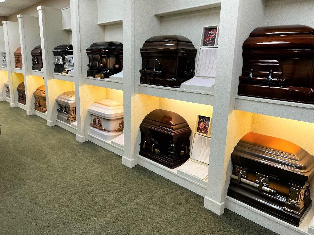 Rows of caskets displayed in illuminated alcoves inside a funeral home.