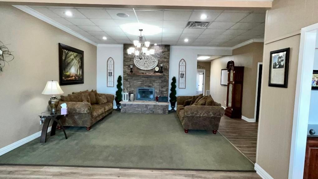 Living room with stone fireplace, sofas, and green carpet.