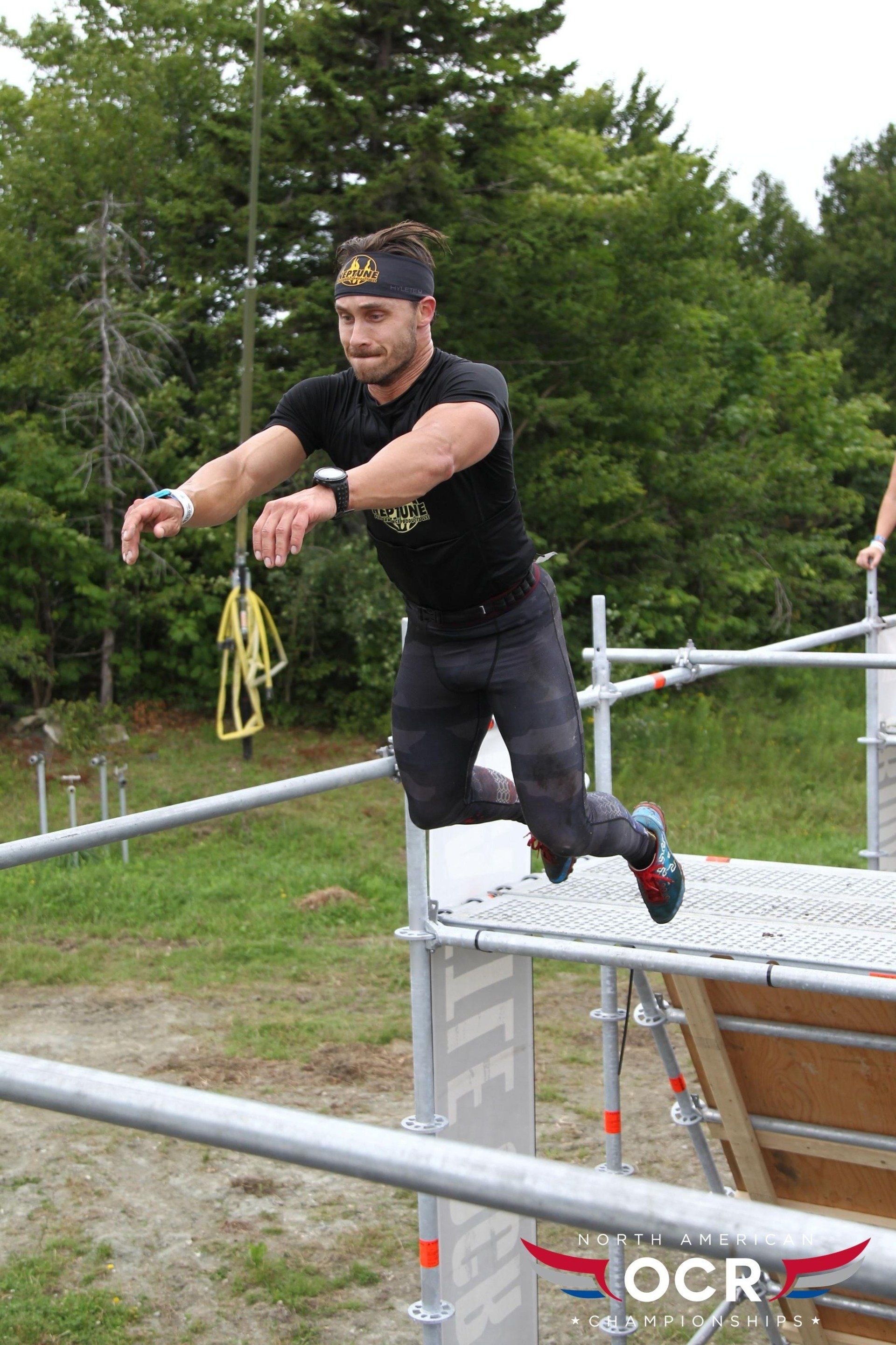 A man is jumping over a metal bar in a race.