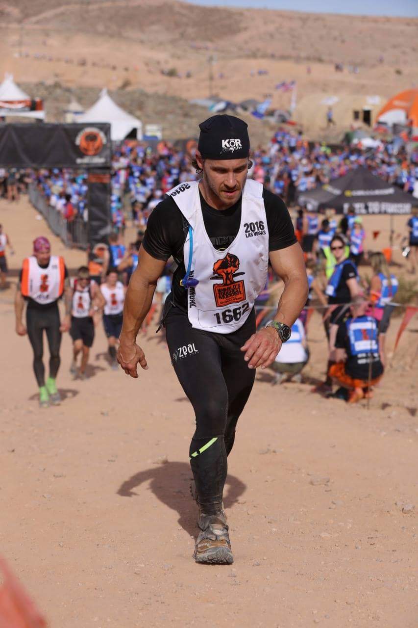 A man is running up a dirt hill in front of a crowd.