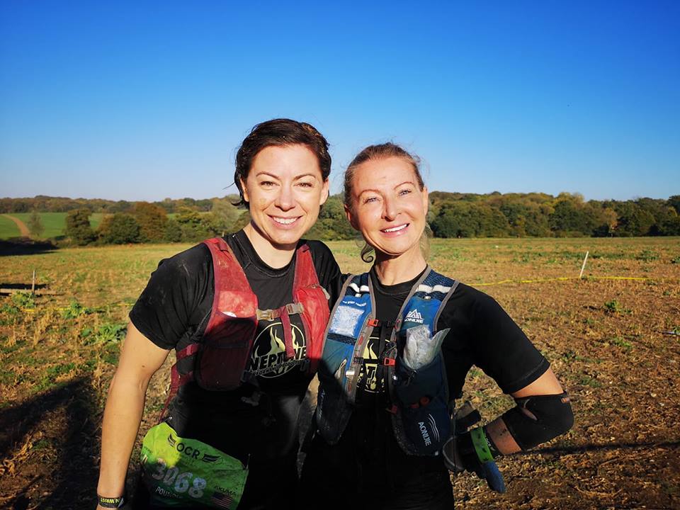 Two women are posing for a picture in a field.