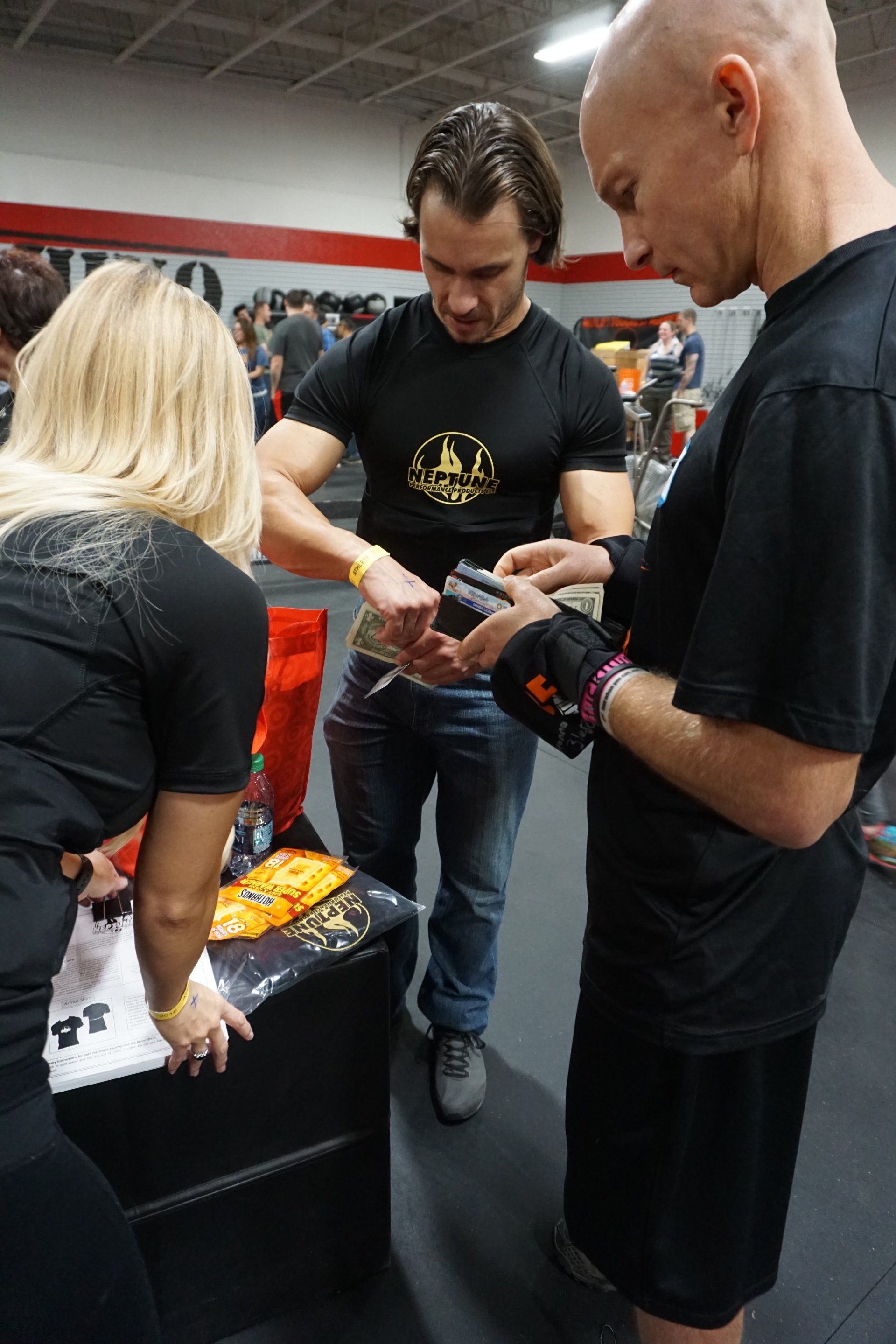 A group of people are standing around a table in a gym.