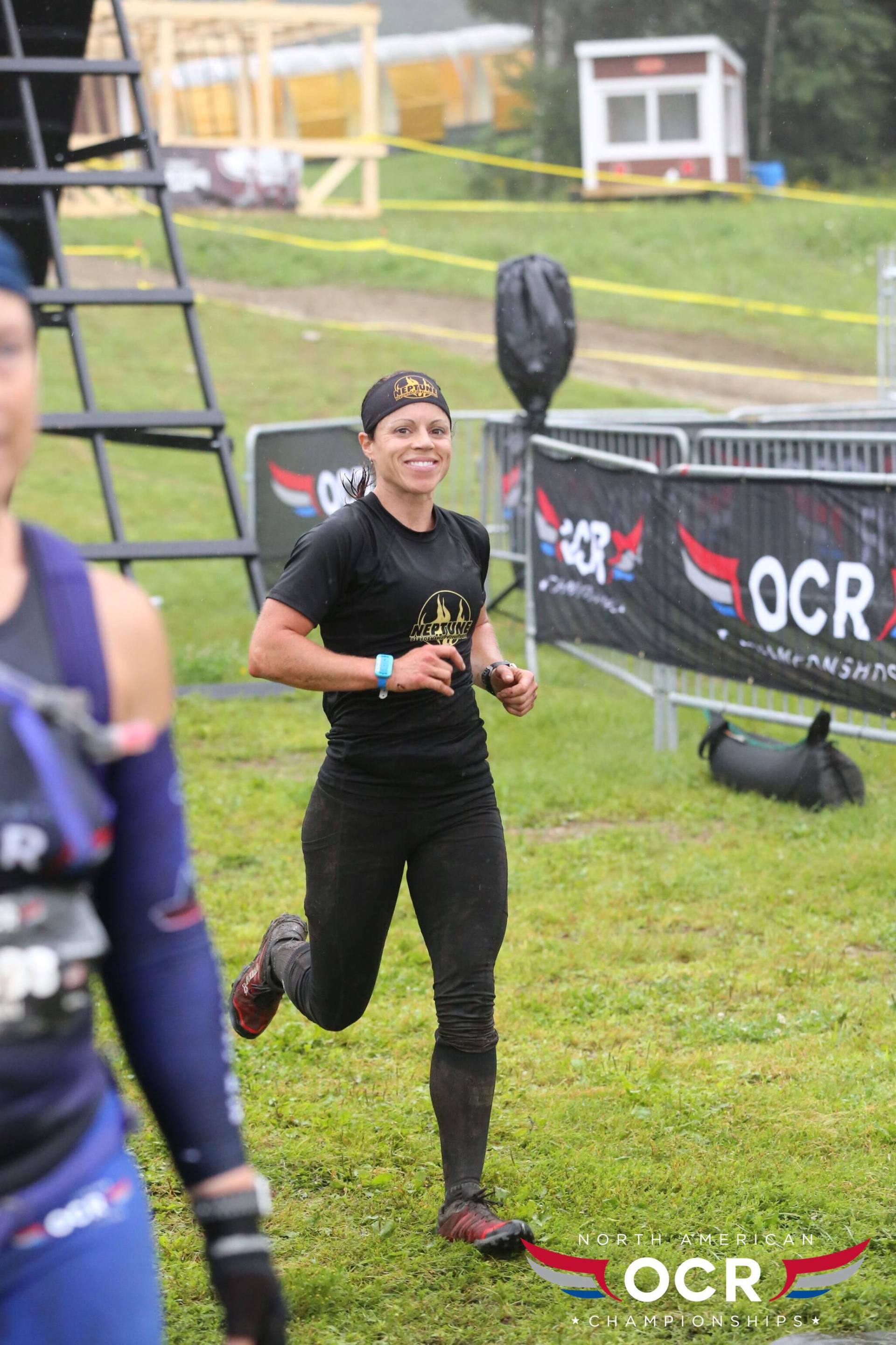 A woman is running in a field with a ladder in the background.