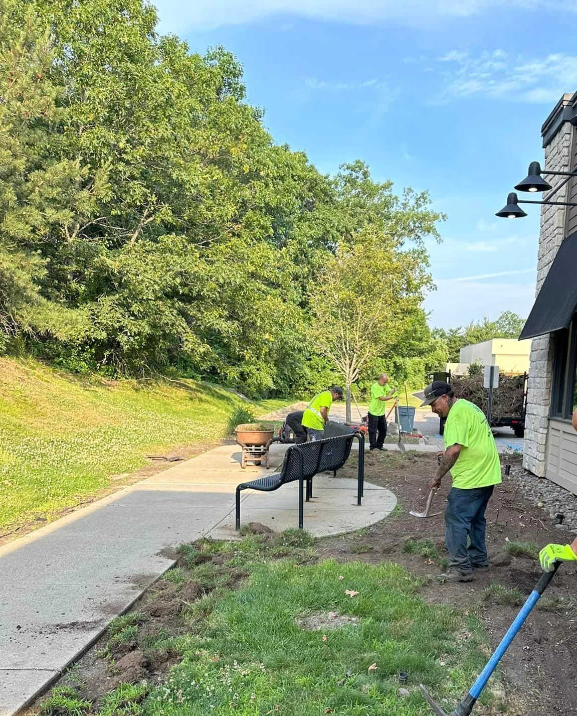A group of people are working on a lawn in front of a building.