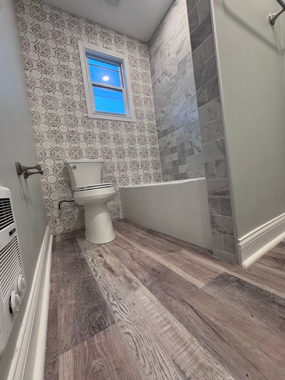Luxury bathroom with granite vanity, large mirror, and a white soaking tub by a window.