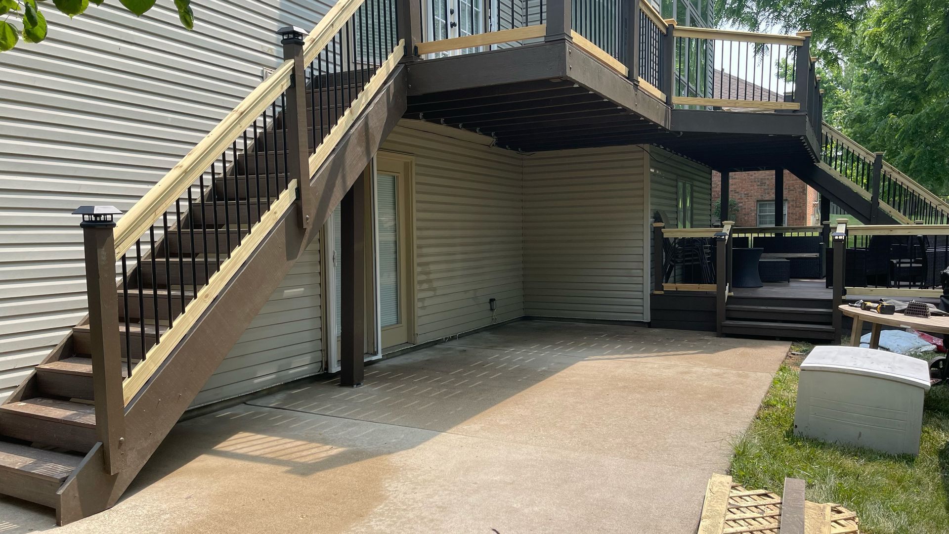House exterior with elevated wooden deck, stairs, and concrete driveway under the deck